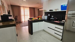 Una cucina funzionale con frigorifero, microonde e macchina per il caffè.