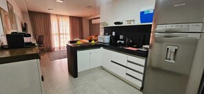 A compact kitchen with a refrigerator, a microwave, and a coffee maker. - Fully furnished apartment in João Pessoa, very close to the beach, with leisure area and garage. (João Pessoa)