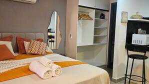Una camera d'albergo con un letto, un armadio, uno specchio e una sedia.