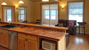 Una cocina con armarios de madera, microondas y una isla grande con pileta.