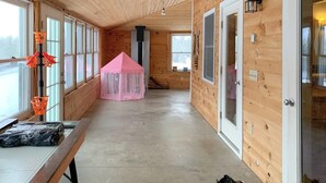 Un interior de madera con un banco, una tienda de campaña rosa y una puerta.