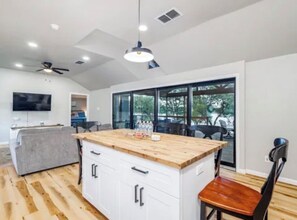 Une cuisine moderne avec un îlot central en bois, des meubles blancs et un ventilateur de plafond.