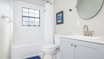 Un baño con bañera, inodoro, lavabo y espejo.