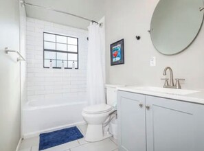 A bathroom with a bathtub, toilet, sink, and a mirror.