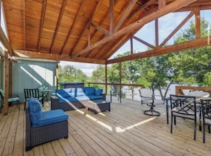 An outdoor deck with wooden flooring, a covered area with a wooden ceiling, and furniture including sofas and chairs. - Private Lake House-Hot Tub-Large Deck-Large Yard (Brownwood)
