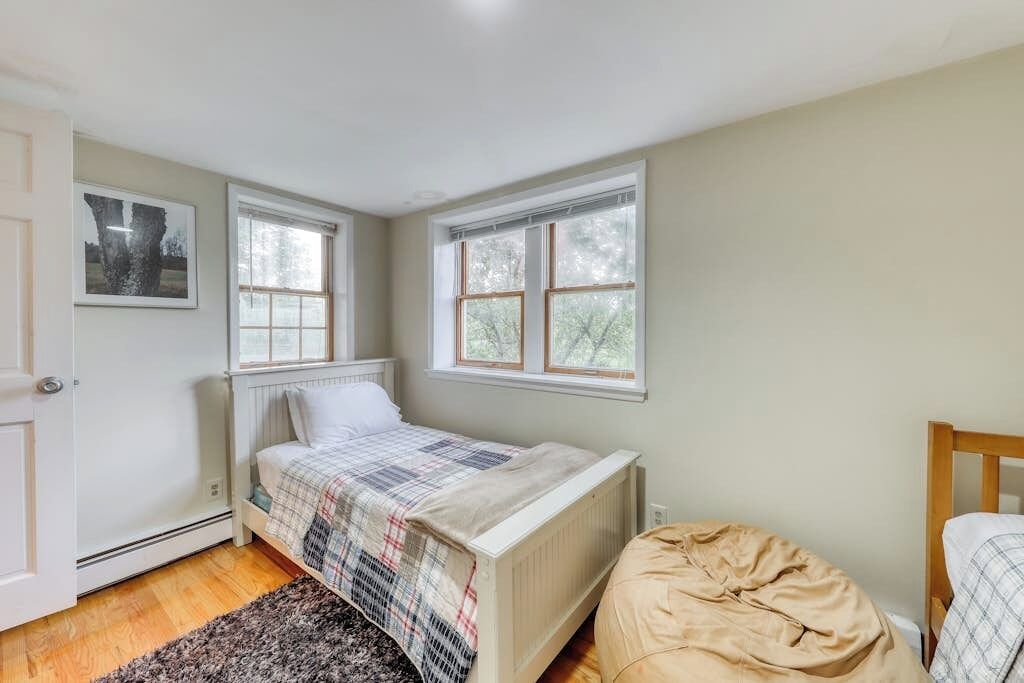 Une chambre à coucher avec un lit, deux fenêtres, un radiateur et une porte.