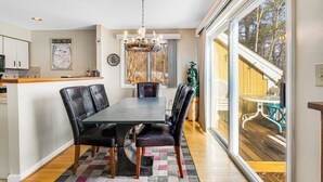 Un comedor con mesa y sillas, una araña y vistas amplias a través de grandes ventanales.
