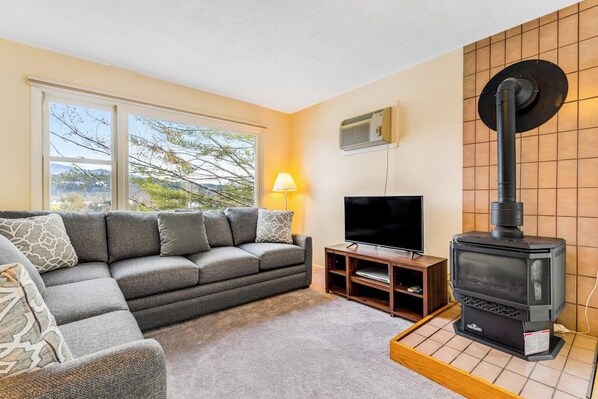 Ein Wohnzimmer mit einer Couch, einem Fernseher und einem Kaminofen.