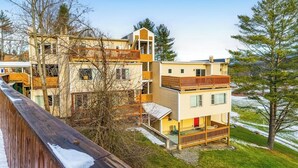 Un edificio de varios pisos con balcones, una terraza de madera y vistas a un paisaje nevado.