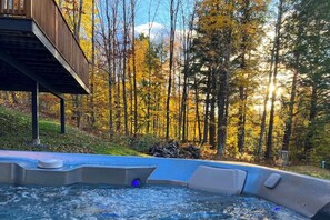 A hot tub in a forested area with a wooden deck and a view of trees. - Three-Level House Near Skiing w/Free WiFi, Private Hot Tub, Gas Fireplace (Stowe)