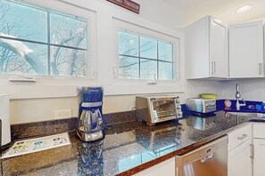 A kitchen with white cabinets, a coffee maker, a toaster, and a sink. - Quaint Getaway Near Town W/ Hot Tub, Large Deck, Sauna & Free WiFi (Stowe)