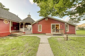 Ein rotes Holzhaus mit Veranda, einem kleinen Anbau und einem Weg zum Eingang.