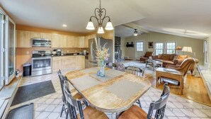 A spacious kitchen with modern appliances, a dining area with a large table, and a cozy living room with a sofa and lamp. - Adorable Getaway w/ Free WiFi, Full Kitchen, & Two Decks (Stowe)