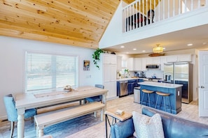 A spacious kitchen with a central island, a dining area with a bench, and a lofted seating area. - Waterfront home on Lake Champlain with pool, hot tub, dock, kayak & canoe (North Hero)