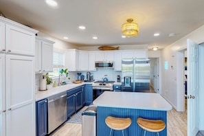 A modern kitchen with white cabinets, stainless steel appliances, and a central island with stools. - Waterfront home on Lake Champlain with pool, hot tub, dock, kayak & canoe (North Hero)