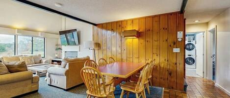 A room with a dining table, chairs, a sofa, a TV, and a washing machine.