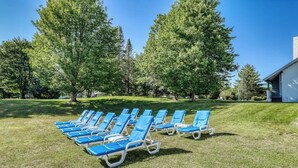 A row of blue lounge chairs on a grassy lawn with trees in the background. - Golf course-front condo with loft, indoor & outdoor pools, hot tub, & game room (Stowe)
