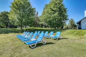 A row of blue lounge chairs on a grassy lawn with trees in the background. - Golf course-front condo with loft, indoor & outdoor pools, hot tub, & game room (Stowe)