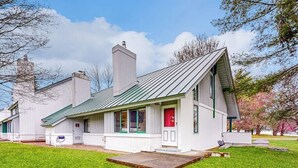 A single-story building with a green roof, a red door, and a small front porch. - Golf course-front condo with loft, indoor & outdoor pools, hot tub, & game room (Stowe)