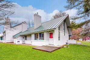 A single-story building with a green roof, a red door, and a small front porch. - Golf course-front condo with loft, indoor & outdoor pools, hot tub, & game room (Stowe)