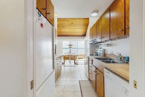 A kitchen with wooden cabinets, a dishwasher, and a view to the outside. - Dog-friendly, home on Lake Champlain with panoramic views of the Green Mountains (North Hero)