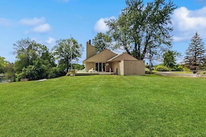 A modern house with a large lawn, a patio, and a chimney. - Dog-friendly, home on Lake Champlain with panoramic views of the Green Mountains (North Hero)