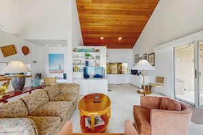 A living room with a sofa, armchairs, a coffee table, and a TV. There is a bookshelf with various items and a painting on the wall. - Dog-friendly, home on Lake Champlain with panoramic views of the Green Mountains (North Hero)