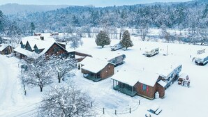 Een besneeuwd landschap met verschillende gebouwen, waaronder vakantiehuisjes en een groot huis met een glazen uitbouw.