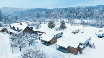 Schneelandschaft mit mehreren Gebäuden, darunter Hütten und ein großes Haus mit Glaserker.