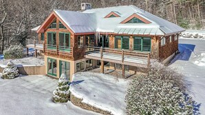 A cabin with a balcony, large windows, and a snow-covered landscape. - Private mountain retreat with a game room, home theater, & jetted tub (Underhill)