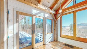 A room with wooden beams, large windows, and a view of a snowy landscape. - Private mountain retreat with a game room, home theater, & jetted tub (Underhill)