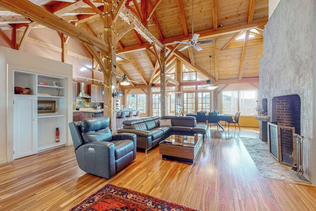 A spacious living area with a wooden ceiling, a fireplace, and a large sectional sofa.