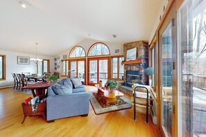 Ein geräumiges Wohnzimmer mit Kamin, großen Fenstern und einem Essbereich.