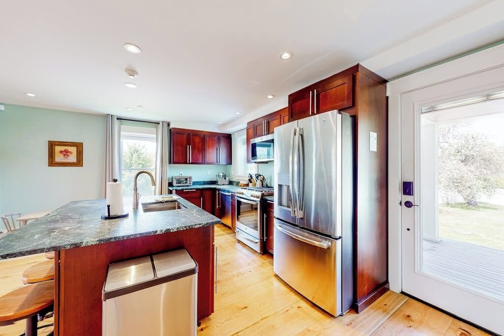 A modern kitchen with a central island, stainless steel appliances, and wooden cabinetry.