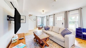 A living room with a sofa, coffee table, and a staircase leading to another room.