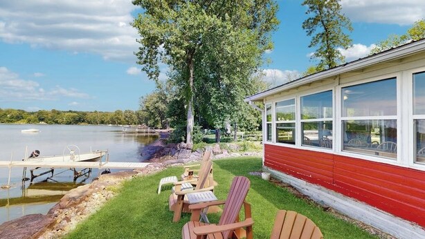 A lakeside cabin with a dock, outdoor seating, and a view of the lake.