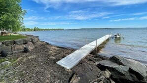 A wooden dock extending into calm water, surrounded by rocks and trees.