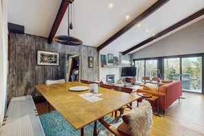 Ein geräumiger Essbereich mit einem Holztisch und Stühlen, einem roten Sofa und einem großen Fenster mit Blick.