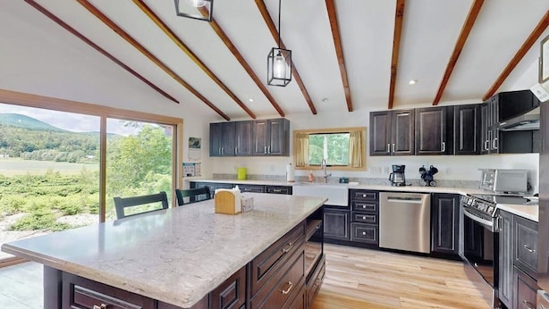 A modern kitchen with a large island, built-in appliances, and a view of the outdoors. - Riverfront house w/ valley & distant mountain views, fireplace, w/d, wifi (Stowe)