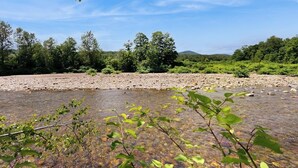 A river with clear water, surrounded by trees and a clear sky. - Riverfront house w/ valley & distant mountain views, fireplace, w/d, wifi (Stowe)