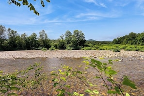 Ein Fluss mit klarem Wasser, umgeben von Bäumen und blauem Himmel.