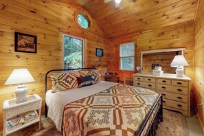 Une chambre dans une cabane en bois, avec un lit, une commode et une fenêtre.