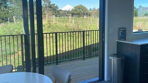 Un balcon donnant sur un champ verdoyant et une montagne.