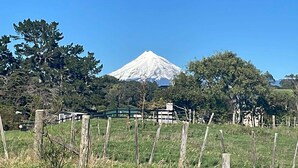 Un paysage rural avec une montagne en arrière-plan, une clôture en bois et des arbres.