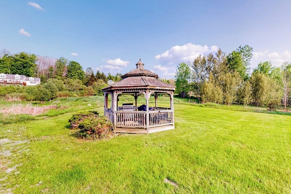 A gazebo in a grassy field with a clear sky.