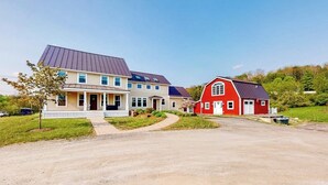 Ett tvåvåningshus med en inglasad veranda och en röd lada.
