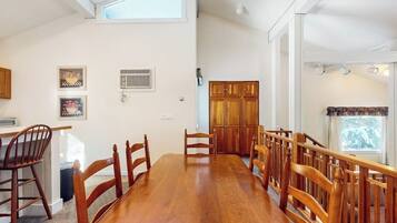 A dining area with a wooden table and chairs, a kitchen area with cabinets, and a window with a view.