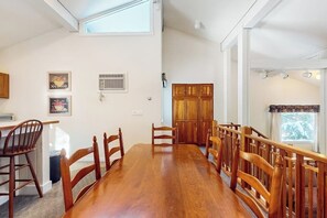 Ein Essbereich mit Holztisch und -stühlen, ein Küchenbereich mit Schränken und ein Fenster mit Blick.