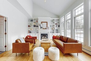 Ein geräumiges Wohnzimmer mit Kamin, Bücherregalen und großen Fenstern.