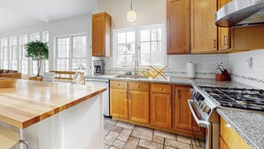 A modern kitchen with wooden cabinets, a built-in stove, and a large window. - Cozy home near park, deck, patio, bbq, soaking tub, TV, basketball, office, w/d (South Burlington)
